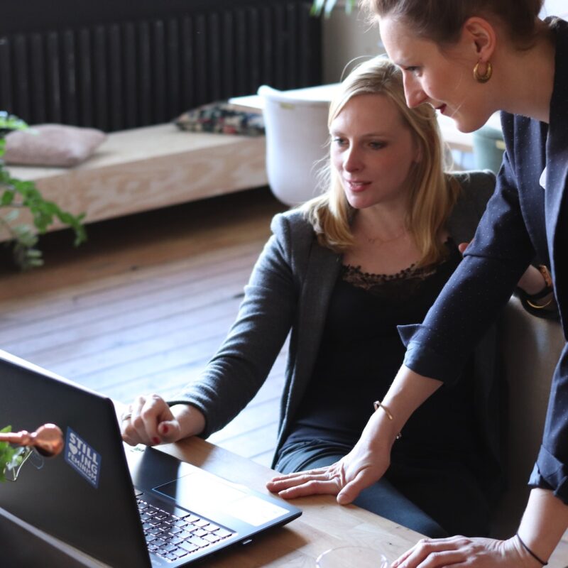 two women looking at a laptop on a table