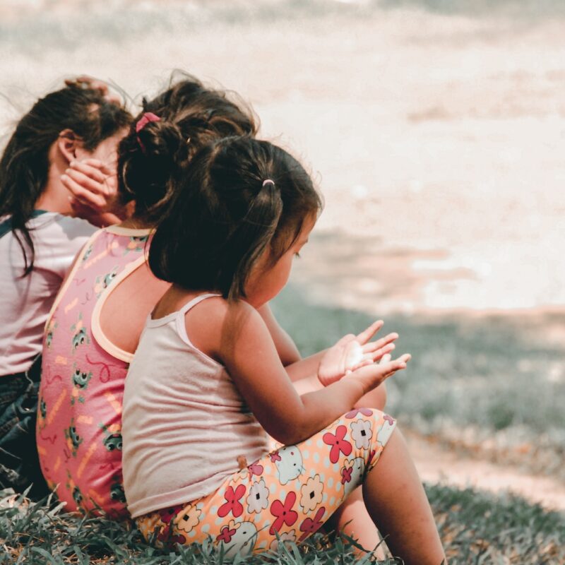 three children sitting on grass